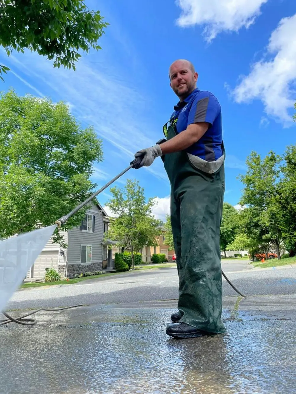 Worker pressure washing a concrete driveway
